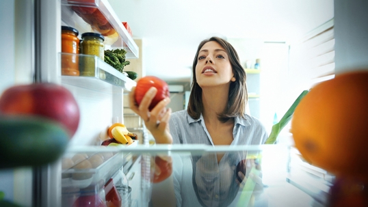 Women grabbing an apple from the fridge